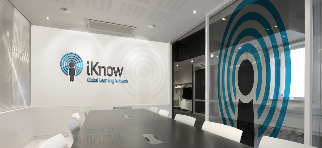 A futuristic and clean, white office with a logo on the wall that reads ‘iKnow, the Global Learning network’” 