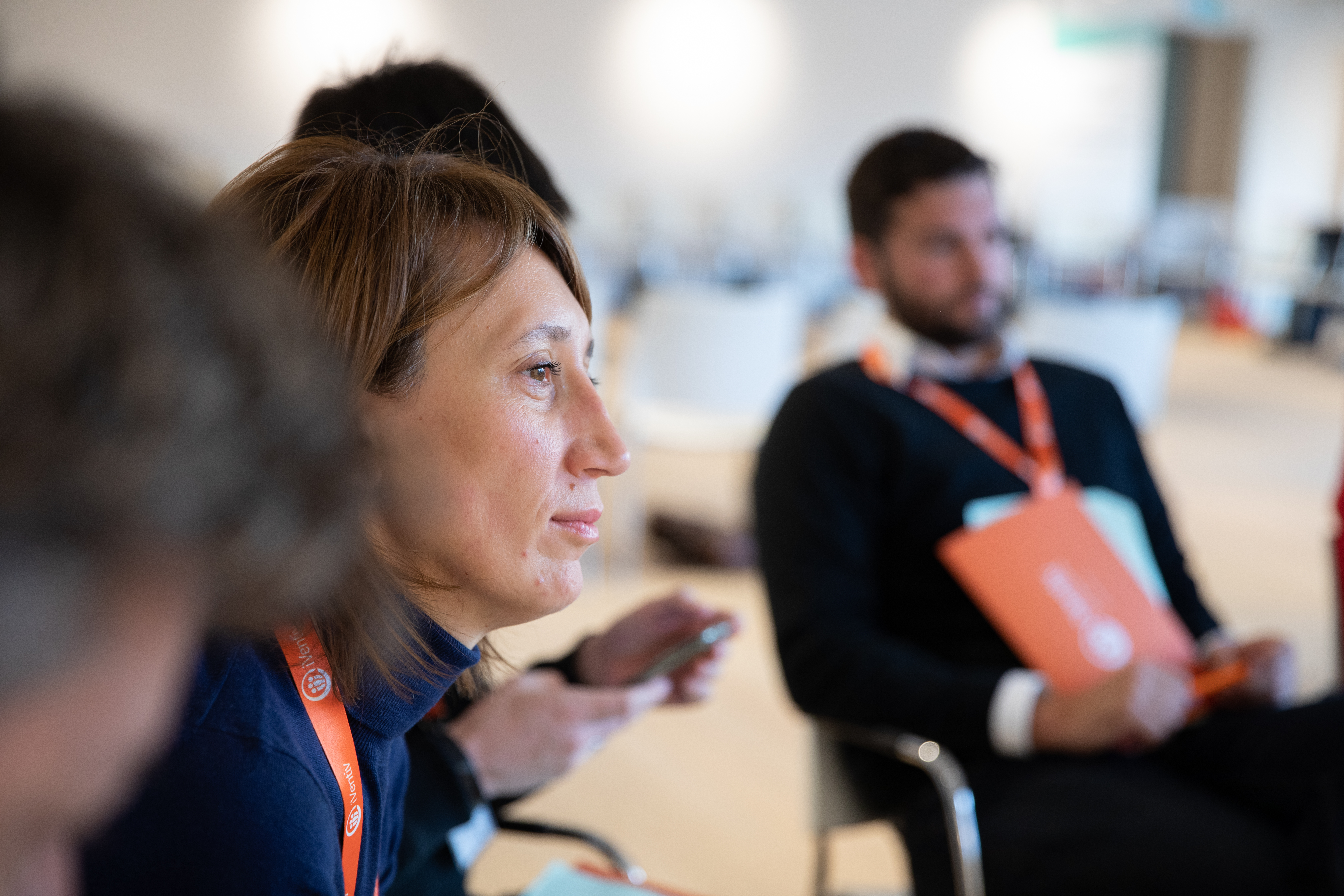 A woman leans forward, listening intently at an executive conference.